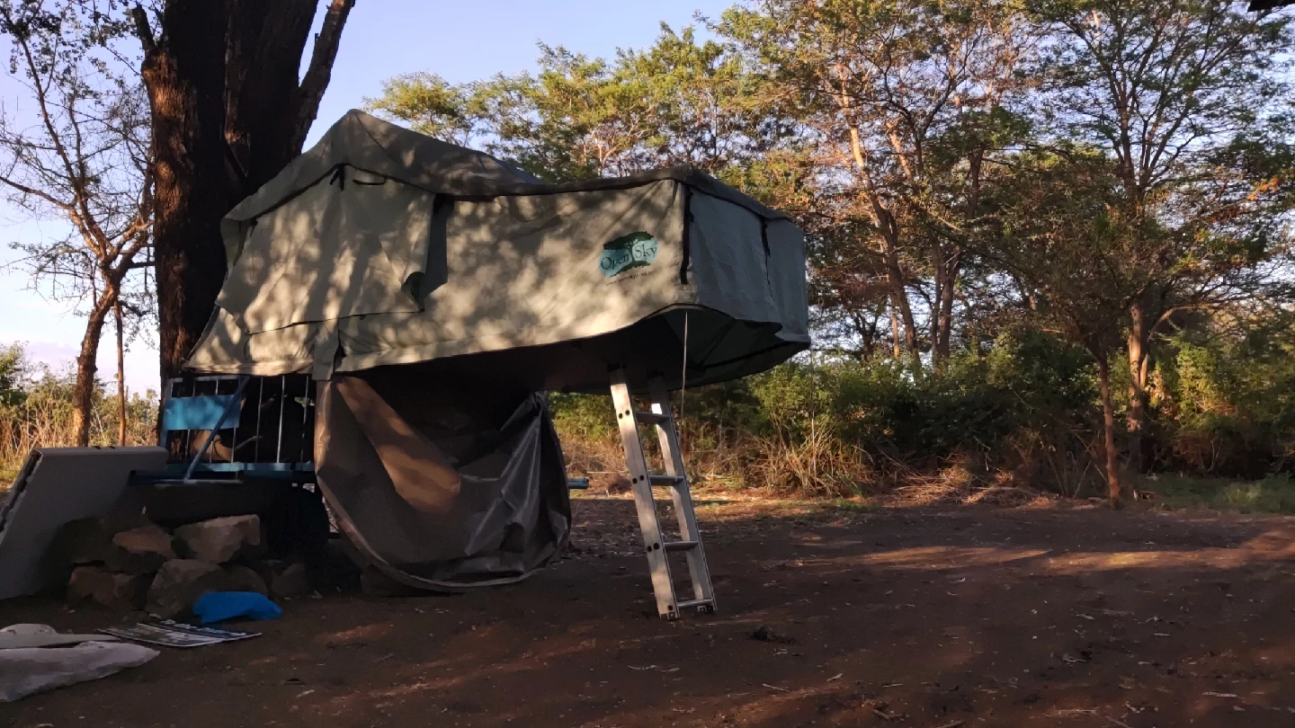 Mkokoteni rooftop tent beneath trees at Thiba River Camp